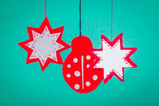 Kolm helkurit rippumas rohekal taustal. Kaks helkurit on tähekujulised ja üks helkur lepatriinukujuline.