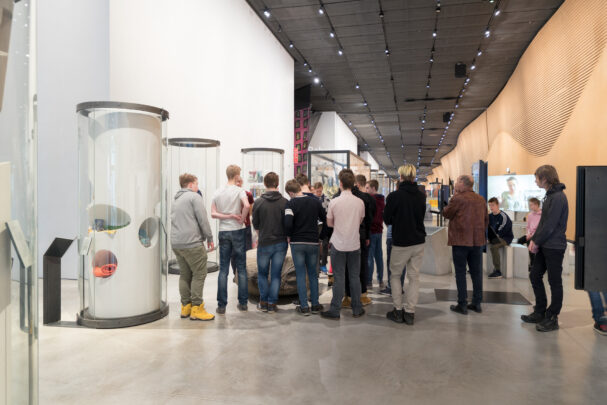 Muuseumi näitusesaalis seisab grupp külastajaid ringis, kuulamas giidi.