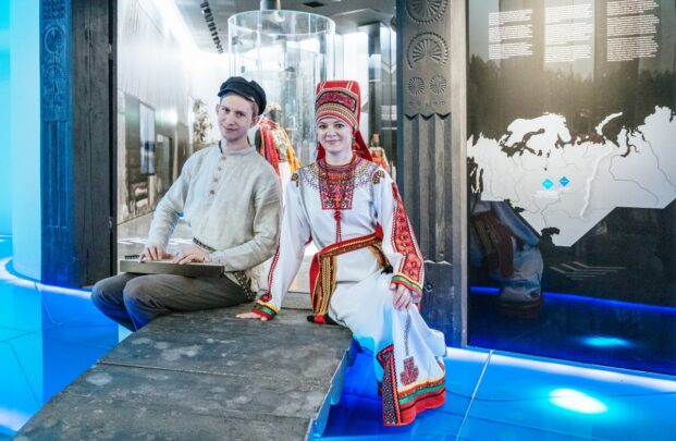 Mees ja naine istumas rahvuslikus riietuses. Valgusküllane keskkond.